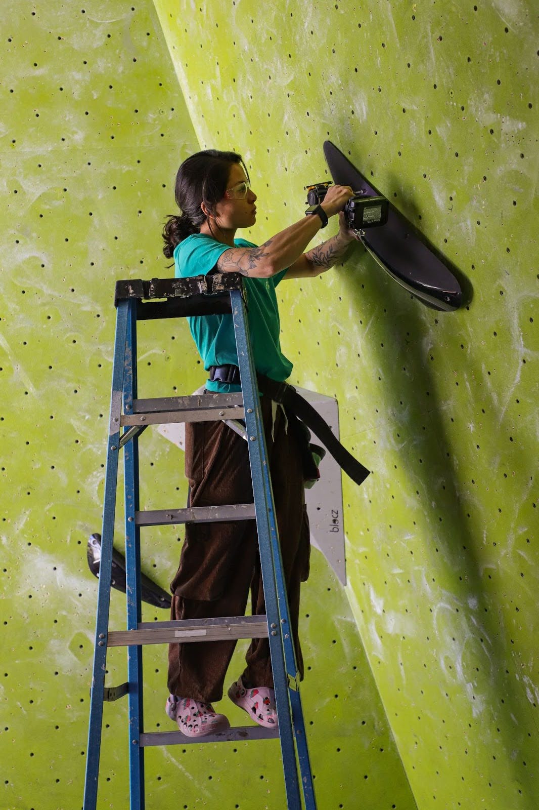 A woman setting climbing holds on a wall